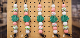 Set of decorative keychains with beads and leaf designs on a pegboard.