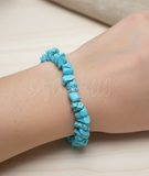 A turquoise beaded bracelet on a wrist with a neutral background