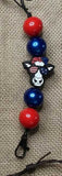 Lanyard with red and blue beads and a black cat-shaped charm on a textured background