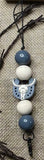 Lanyard with grey and white beads and a silicone bull head charm on a textured fabric background