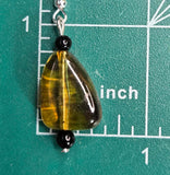 May include: A pair of earrings with a teardrop-shaped green and yellow glass bead, a black bead, and a silver hook.