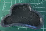 May include: A gray rubber silicone mold for making a cowboy hat. The mold is detailed with a textured surface and a raised design of a cowboy hat.