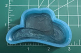 May include: A blue silicone mold for making a cowboy hat. The mold is about 3 inches wide and 2 inches tall.