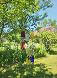 Handmade lotus flower wind chime with rainbow stained glass panes, decorative beads, and vintage skeleton keys hanging in a sunny garden.