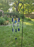 Lotus flower glass wind chime with blue and silver Texas-shaped charms in a green garden