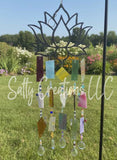 Handcrafted lotus flower wind chime featuring multicolored stained glass panels and crystal prisms hanging in a garden.