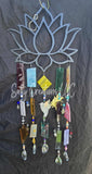 Decorative metal sun catcher with colorful beads and crystals on a textured gray background