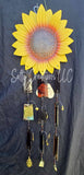 Decorative sunflower wall art with hanging elements on a dark background