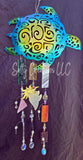 Decorative wind chime with turtle design and hanging beads on a dark background