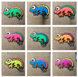 Colorful handcrafted wooden chameleon fridge magnets displayed in a grid on a textured background