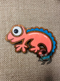 Orange and blue handcrafted wooden chameleon fridge magnets displayed in a grid on a textured background